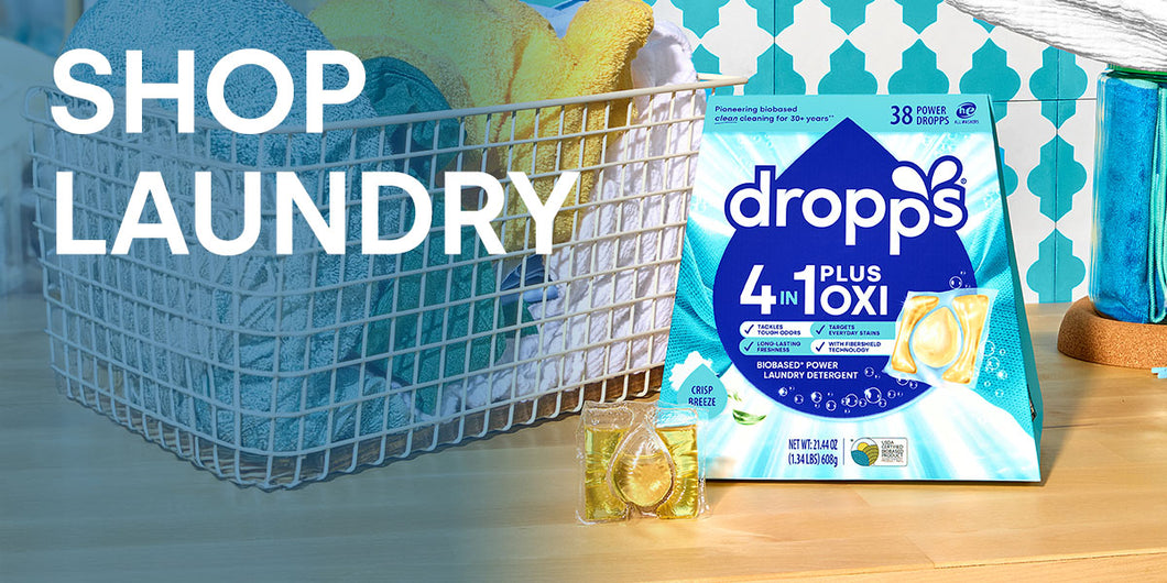 Dropps laundry detergent packaging with a basket of clothes in the background. SHOP LAUNDRY.