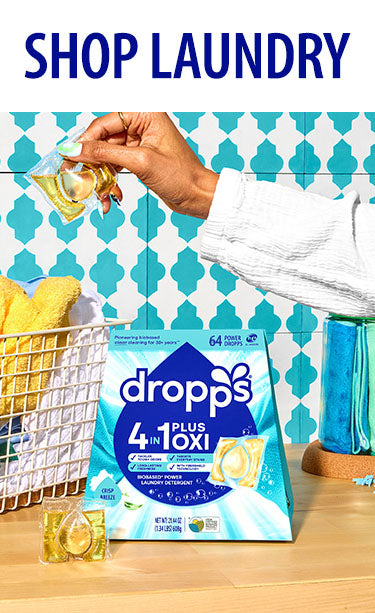 Dropps laundry detergent packaging with a basket of clothes in the background. SHOP LAUNDRY.