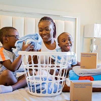 Mom and two children smelling clothes cleaned with Dropps