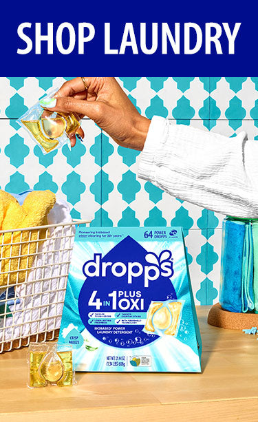 Dropps laundry detergent packaging with a basket of clothes in the background. SHOP LAUNDRY.