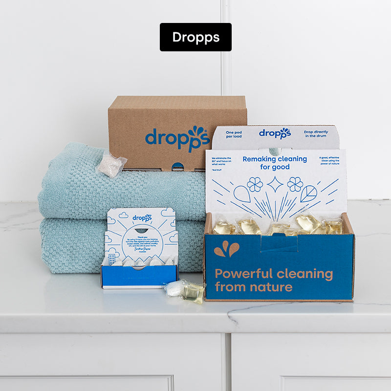 Dropps laundry detergent in a laundry room setting with folded towels